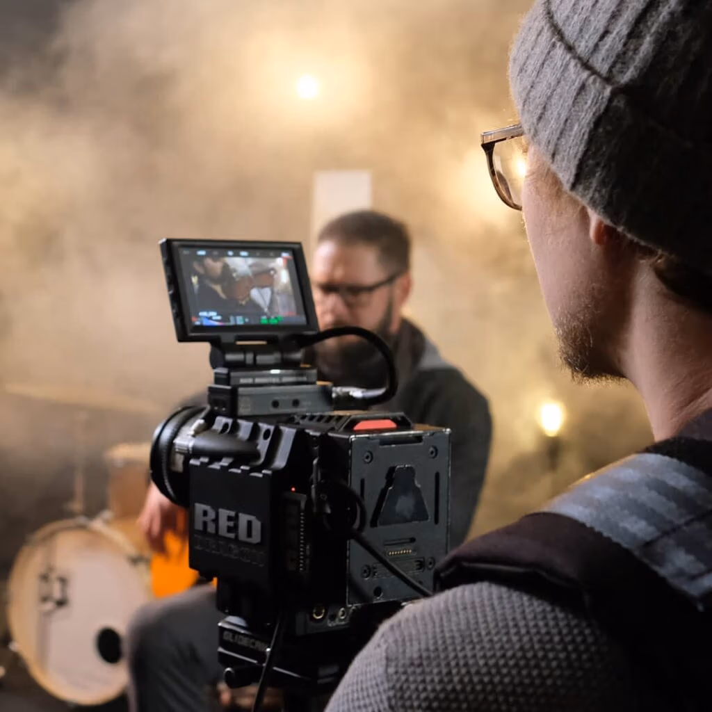 Kameramann arbeitet mit einer RED-Kamera und filmt einen Musiker in nebliger Studioatmosphäre - Bild von Spreadfilms