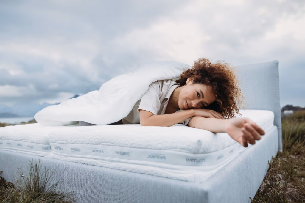 Foto einer Outdoor-Lifestyle-Szene: Frau liegt auf einer Wenatex-Matratze und entspannt unter einer Decke - von Spreadfilms