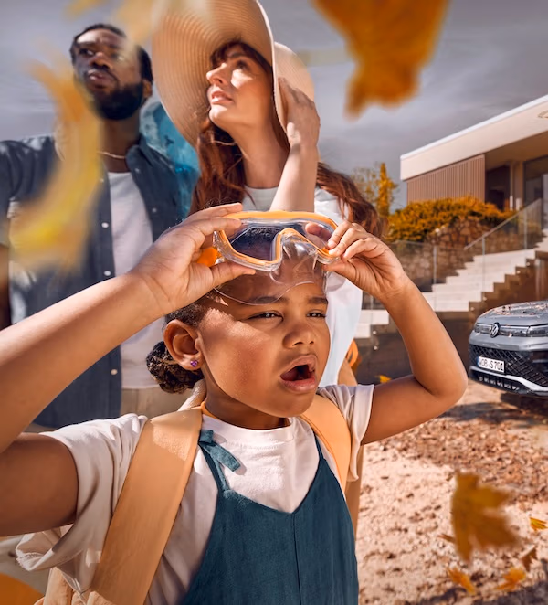 Familie im Herbst, Kind mit schaut fasziniert in die Luft, modernes Fahrzeug im Hintergrund– Szenenbild aus einem VW-Werbespot