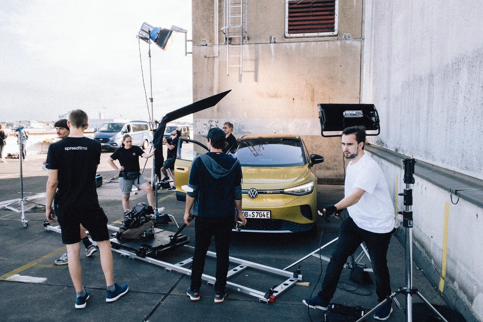 Spreadfilms Filmset mit Crew, Kamera-Setup und Lichttechnik bei einem Werbedreh für ein gelbes Elektrofahrzeug von VW