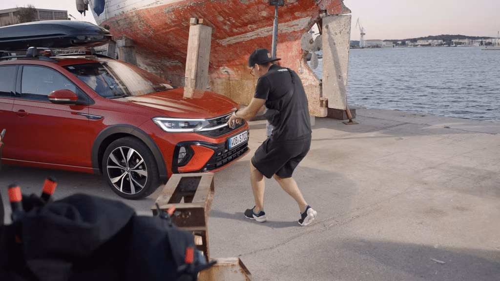 Behind-the-Scenes Aufnahme eines Spreadfilms-Drehs – Kameramann filmt einen roten Volkswagen vor maritimer Kulisse am Hafen für einen Imagefilm