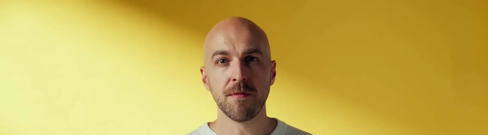 remberg CEO David Hahn im Produktvideo von Spreadfilms ruhig in die Kamera blickend vor gelbem Studiohintergrund