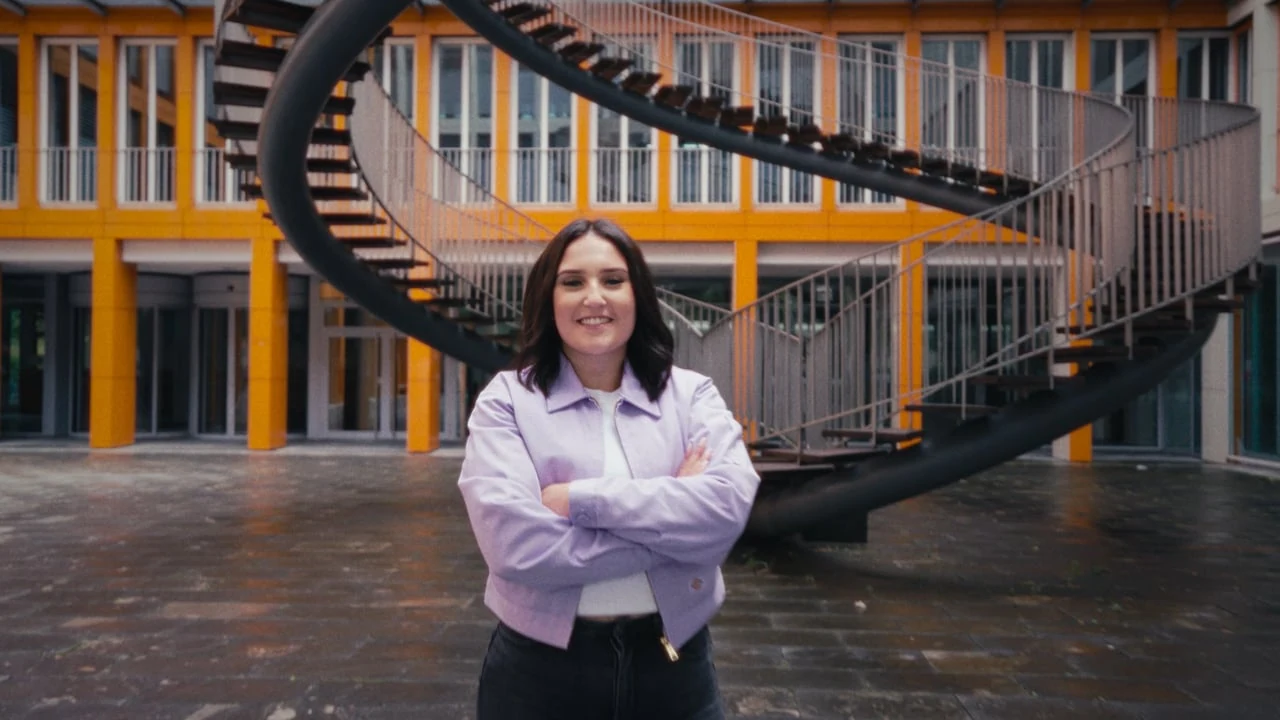 Mitarbeiterin vor dem charakteristischen Gebäude der Agentur für Arbeit München im Recruitingfilm